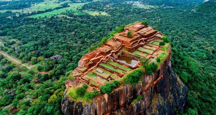 Dramatic aerial view of Sigiriya rock plateau rising above dense Sri Lankan jungle.