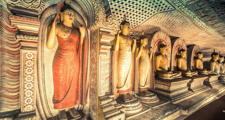 Estatuas doradas de Budas de pie y sentados adornan las cámaras tenuemente iluminadas del Templo de las Cuevas de Dambulla.
