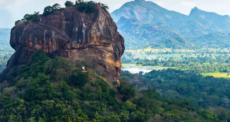 La dramática ciudadela rocosa de Sigiriya se alza sobre la densa selva con montañas distantes al fondo.