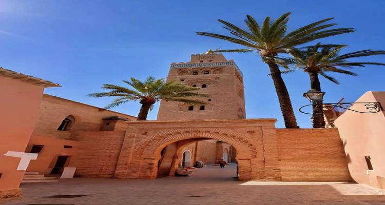 Tall Koutoubia Mosque minaret framed by palms under clear blue sky in Marrakesh