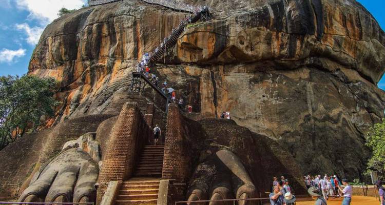 Lange Besucherschlange steigt schmale Treppen die steile Felswand von Sigiriya hinauf, vorbei an riesigen gemauerten Löwenpranken.