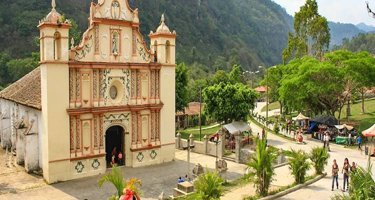 Historic colonial church set against a green hillside with visitors nearby