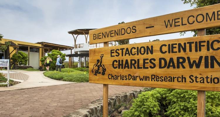 Panneau d'entrée de la Station de Recherche Charles Darwin avec des visiteurs en arrière-plan