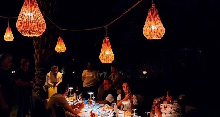 Scène de dîner nocturne en plein air avec des lanternes suspendues éclairant les invités à une longue table