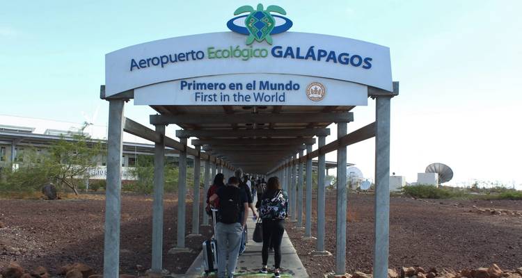 Des voyageurs marchant dans la passerelle couverte de l'Aéroport Écologique des Galápagos.
