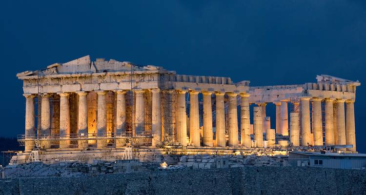 Het Parthenon verlicht tegen een diepblauwe avondhemel, waarbij de klassieke zuilen worden benadrukt.