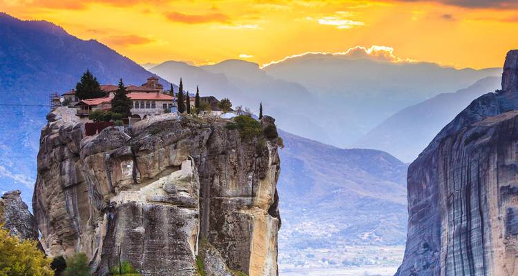 Klooster op een dramatische rotspilaar in Meteora tijdens een kleurrijke zonsondergang.