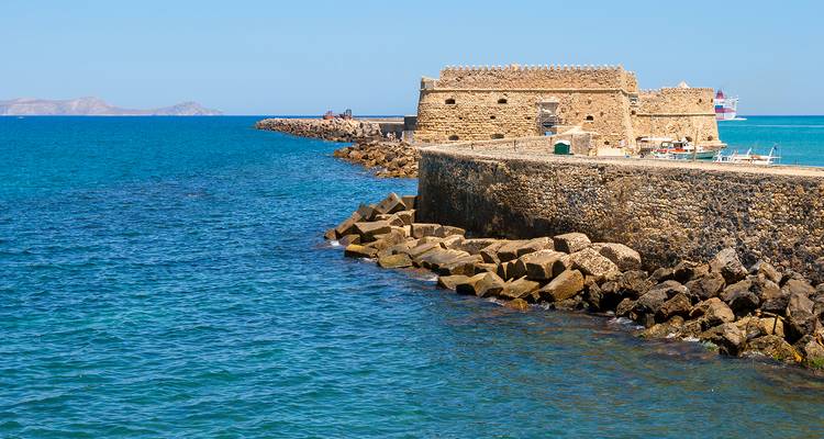 Stenen Venetiaanse vesting die de ingang van de haven van Heraklion bewaakt tegen een levendige blauwe zee.
