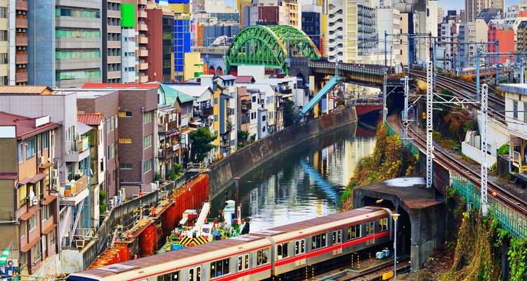 Las vías del tren urbano cruzan un canal fluvial rodeadas de coloridos edificios de gran altura en el centro de Tokio.