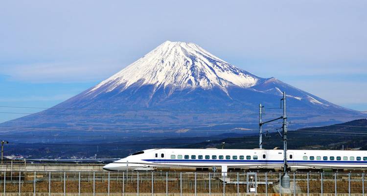 Schneebedeckter Mount Fuji, der sich über einen schnell fahrenden Shinkansen-Hochgeschwindigkeitszug erhebt