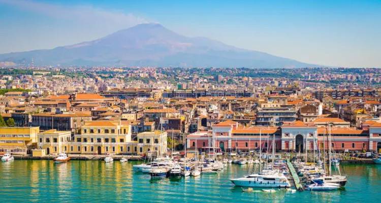 Panoramisch uitzicht op Catania's waterfront jachthaven met de Etna die zich achter de stad verheft.