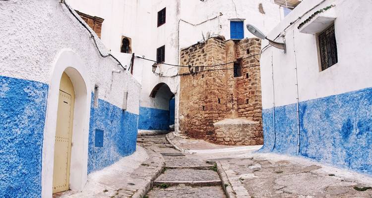 Witgekalkt steegje met blauwe onderste wanden en stenen bogen in Rabat's Kasbah van de Udayas