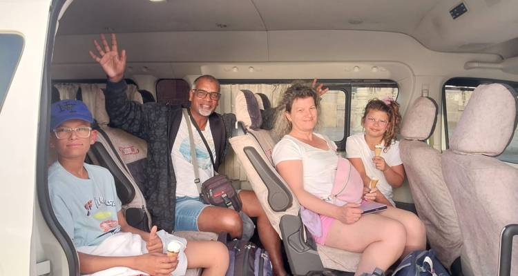 Grupo familiar sentado dentro de una camioneta turística sonriendo y comiendo helado durante su viaje.