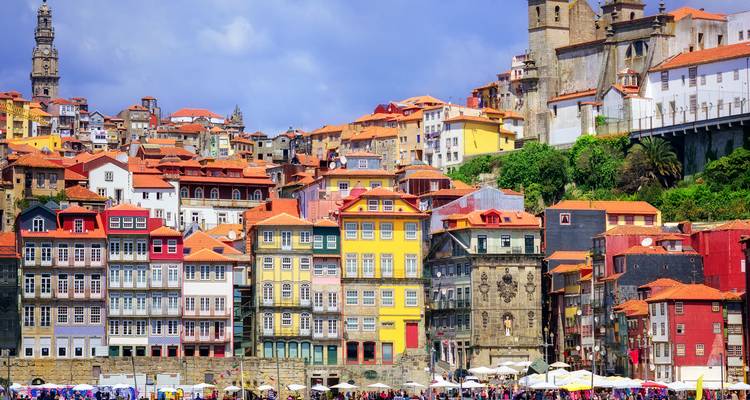 Fachadas de colores brillantes del frente marítimo de la Ribeira de Oporto escalonadas por la ladera bajo un cielo azul.
