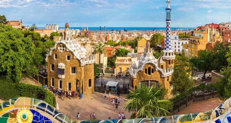 Des bancs en mosaïque fantaisistes surplombent les maisons de garde en pain d'épice du parc Güell avec Barcelone qui s'étend jusqu'à la mer au-delà.