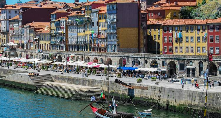 Bâtiments colorés au bord de la rivière du quartier de la Ribeira de Porto avec des cafés et des gens le long de la promenade du front de mer.