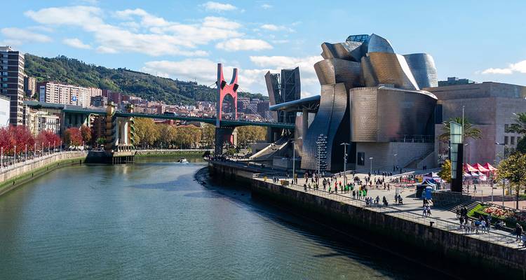 La façade chatoyante du Musée Guggenheim Bilbao au bord de la rivière et la passerelle moderne.