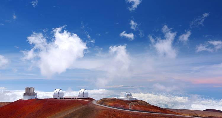 Sommet du Mauna Kea avec des observatoires astronomiques se détachant sur des nuages spectaculaires haut au-dessus de l'île.