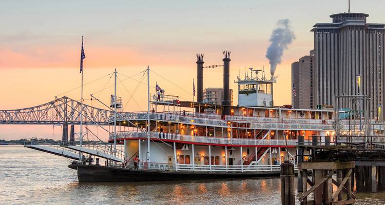 Historische rivierstoomboot aangemeerd in New Orleans met rook opstijgend bij zonsondergang.