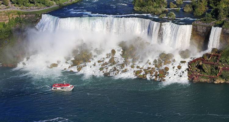 Vue aérienne de la section des chutes américaines des chutes du Niagara avec un bateau de tourisme en dessous.