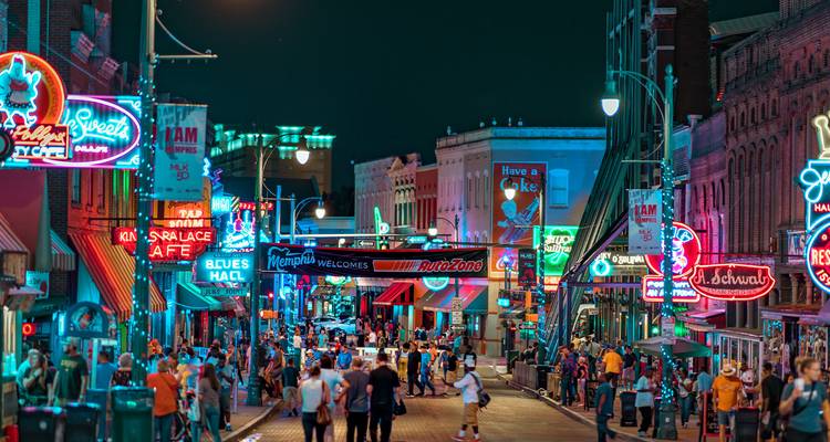 Nachtszene der Beale Street, beleuchtet von bunten Neonschildern, mit Menschenmengen, die die lebendige Atmosphäre genießen.