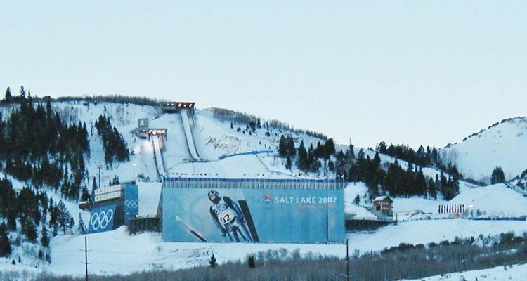 La rampa de salto de esquí de los Juegos Olímpicos de Salt Lake 2002 se encuentra en una ladera nevada con un gran mural de un esquiador.