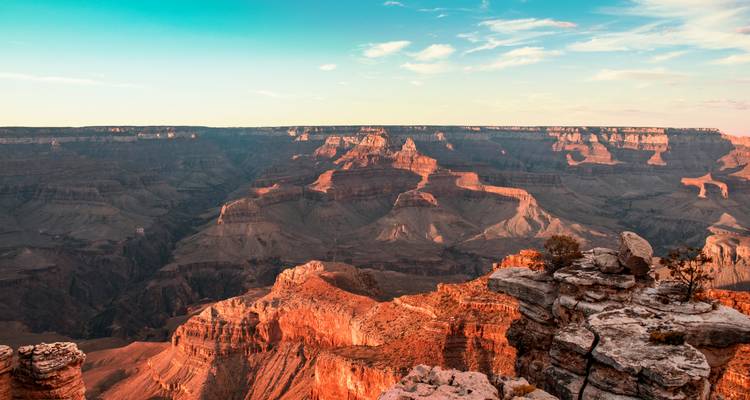 Vaste panorama du Grand Canyon au coucher du soleil mettant en valeur les falaises stratifiées et les gorges profondes.