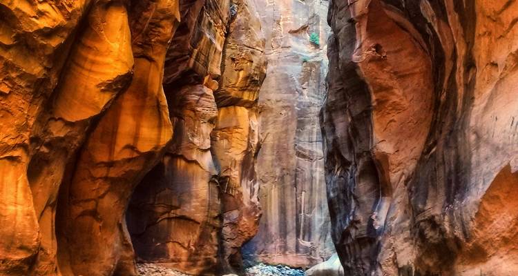 Paredes estrechas de cañón de ranura de color rojo-naranja con rayos de luz y arenisca texturizada.