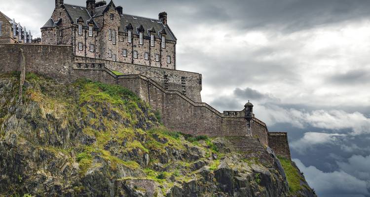 Edinburgh Castle troont op zijn rotsachtige klif en torent boven de stad uit onder donkere grijze luchten.