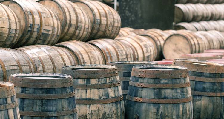 Stapels verouderde eiken vaten in een traditioneel whisky-rijpingsmagazijn