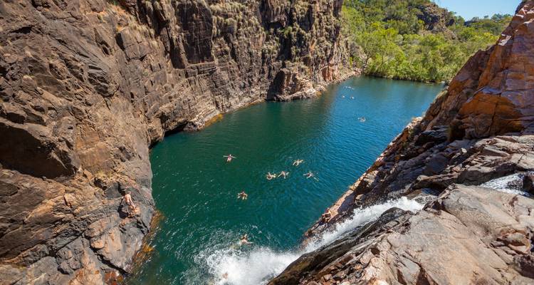Los nadadores disfrutan de una piscina esmeralda profunda en la base de una cascada dramática de desfiladero en el interior.