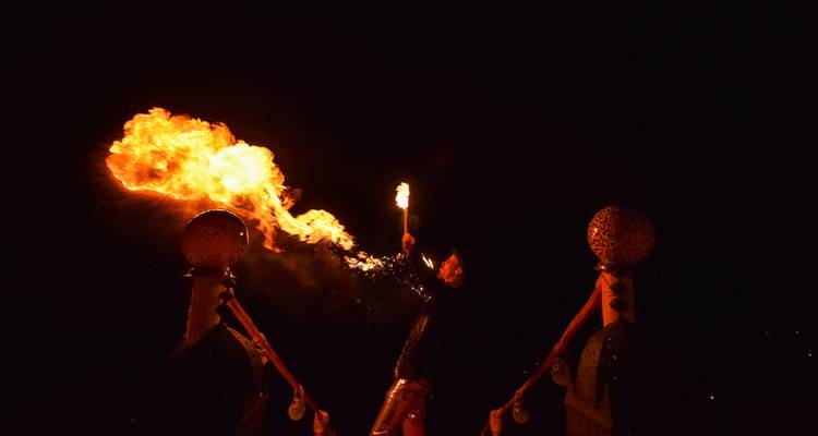 El artista exhala una dramática columna de fuego hacia el cielo oscuro durante un espectáculo en un campamento del desierto.