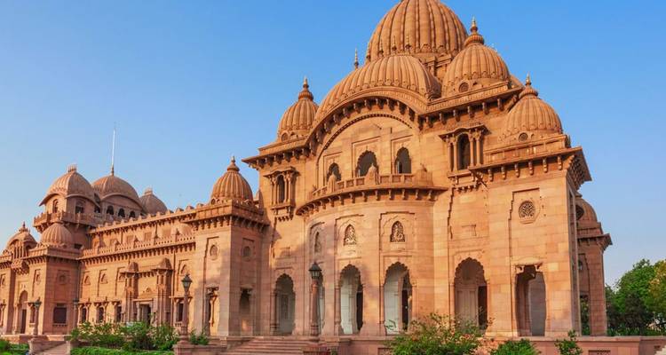 Grand sandstone temple with domes and arches under clear blue sky