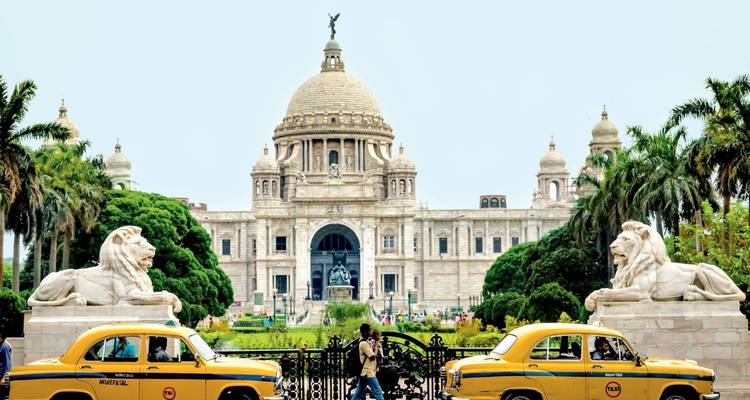 Victoria Memorial framed by palm trees and vintage yellow taxis on a bright day