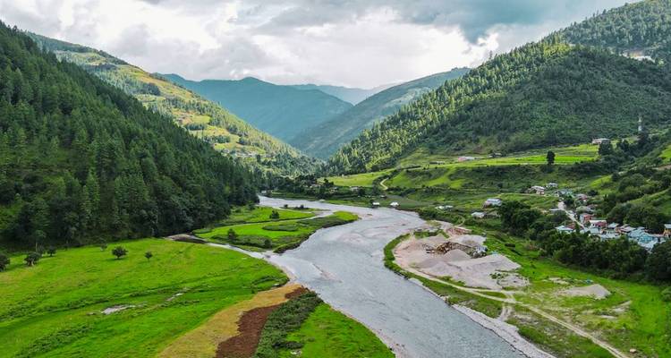 Serene mountain valley with winding river, green meadows and forested slopes