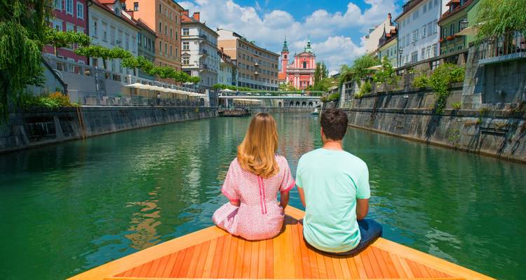 Couple assis à la proue du bateau naviguant sur le canal de Ljubljana vers l'église rose