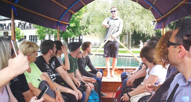 Groupe de touristes assis à l'intérieur d'un bateau pletna couvert écoutant le guide rameur