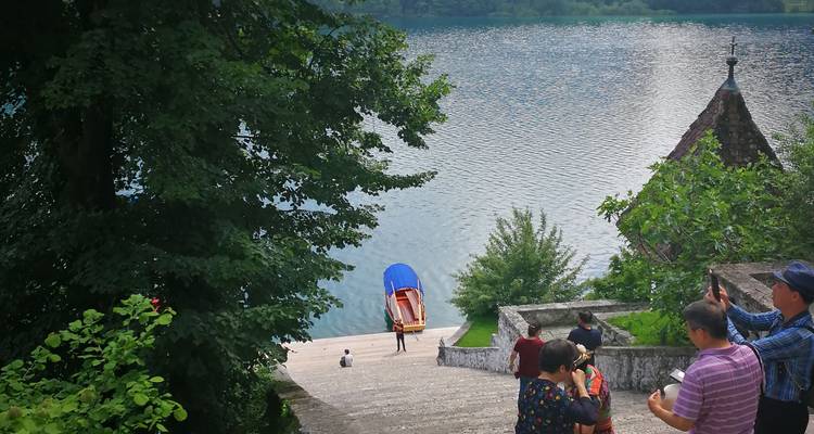 Les touristes descendent des marches en pierre vers l'embarcadère sur le lac de Bled