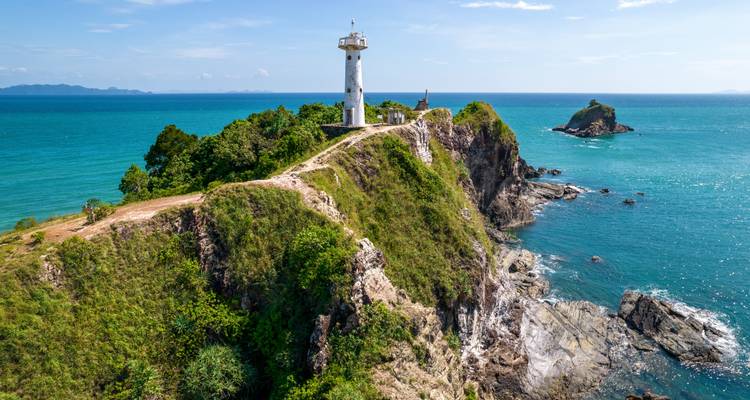 Weißer Leuchtturm auf einer schroffen Klippe über türkisem Meer auf Koh Lanta.