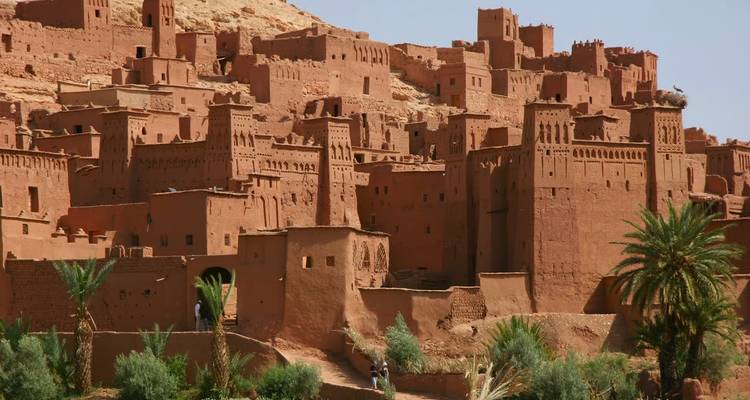 Torres rojo óxido de la kasbah de Ait Benhaddou agrupadas en una ladera desértica