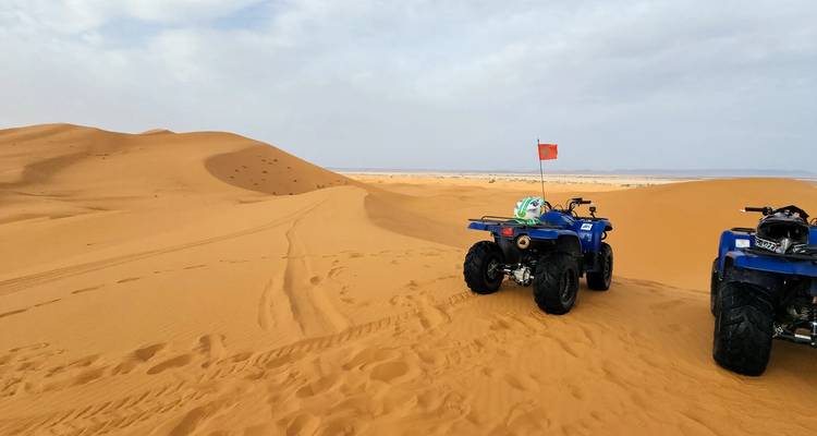 Dos cuatriciclos azules estacionados en una duna azotada por el viento del Sahara listos para la aventura