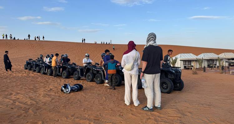 Los participantes se reúnen alrededor de una fila de vehículos todo terreno estacionados en una duna de arena abierta antes de la partida.