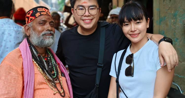 Traveler friends posing with a bearded holy man adorned in colorful beads.