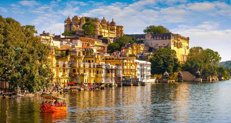Colorful palaces and waterfront homes lining Lake Pichola under golden light.