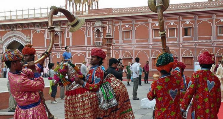 Performers in bright traditional attire play long horns inside Jaipur’s City Palace.