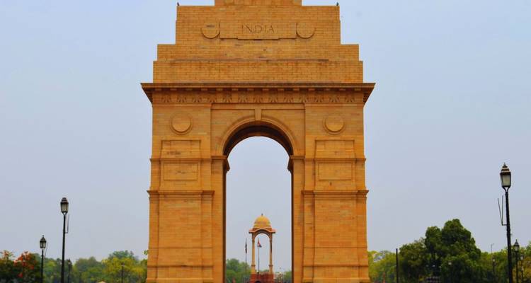 Der Sandsteinbogen des India Gate, der hoch gegen einen blassen Himmel aufragt.