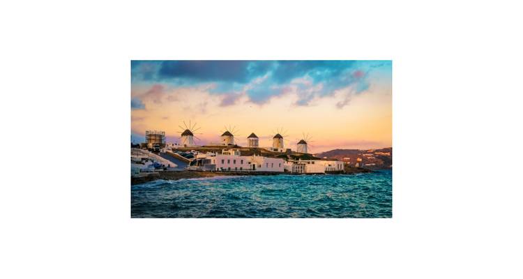 Molinos de viento de Mykonos alineados a lo largo de la costa al atardecer con colores vibrantes del cielo, enmarcados por un margen blanco.