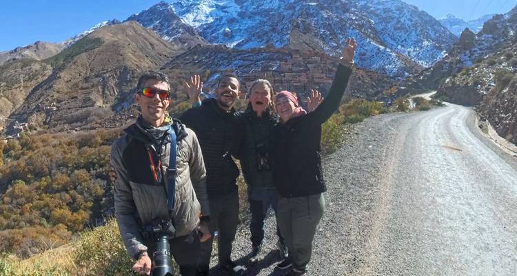 Gruppen-Selfie auf einer Bergstraße mit schneebedeckten Atlas-Gipfeln im Hintergrund.