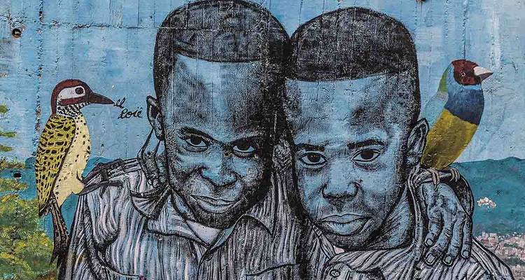 Murale urbaine colorée représentant deux jeunes avec des oiseaux sur un mur bleu vif.