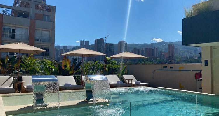 Une piscine sur le toit avec des cascades surplombe un horizon de gratte-ciel modernes.